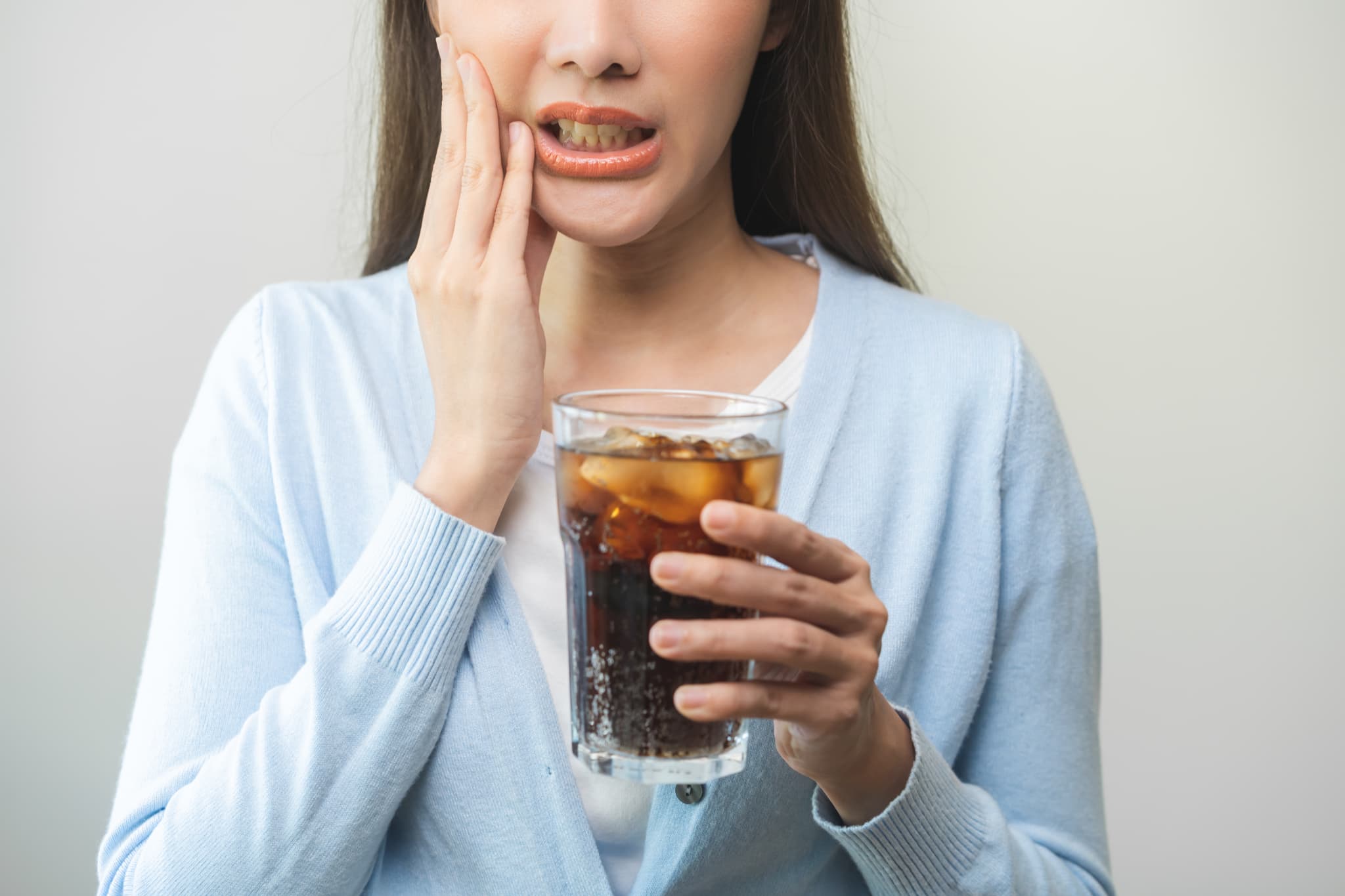 セラミック治療後に冷たい飲み物がしみる女性