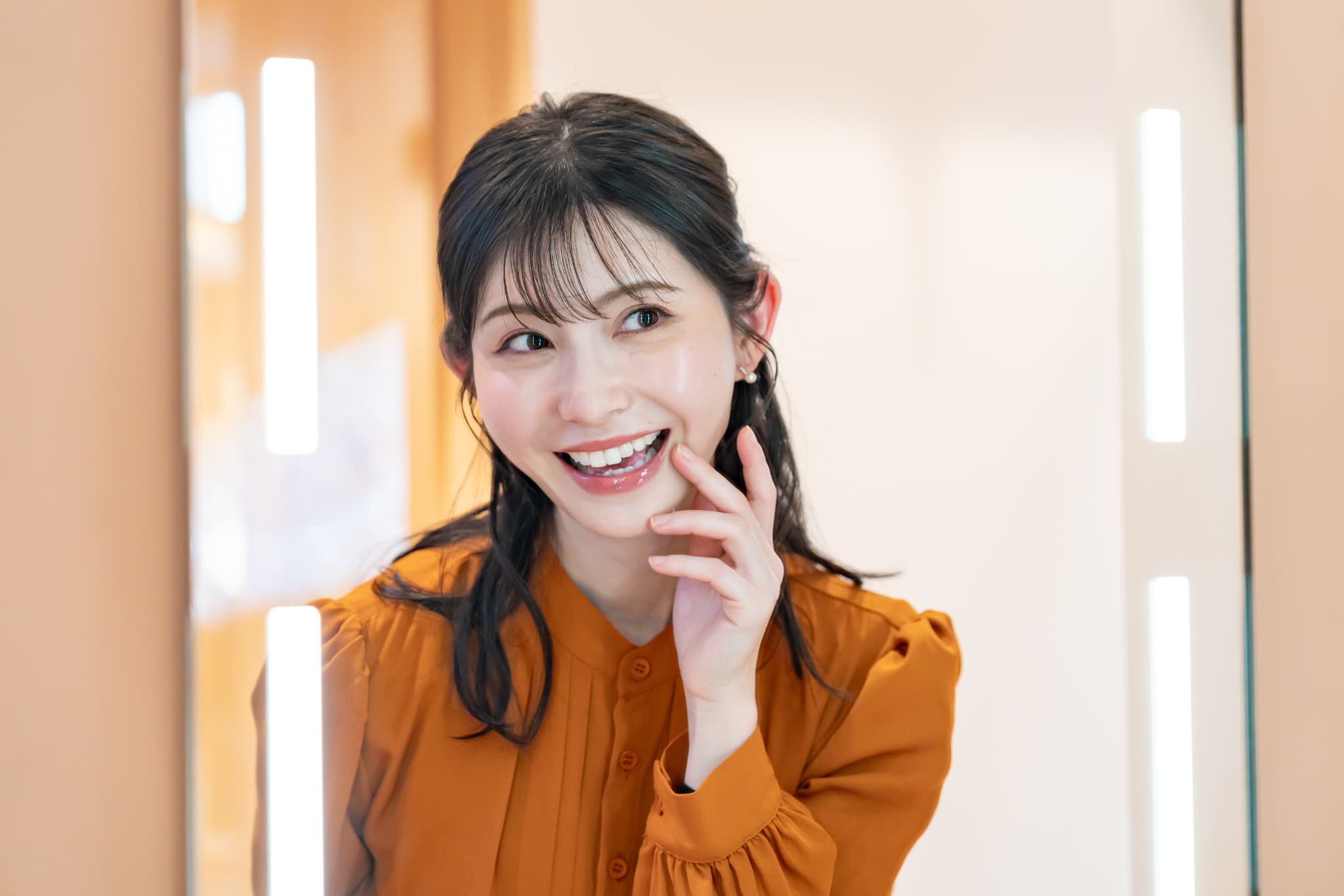 ホワイトニングで白くなった歯を鏡で確認する女性