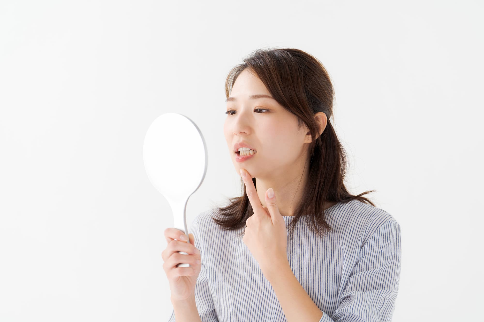 歯ぐきが黒くなり鏡で確認する女性
