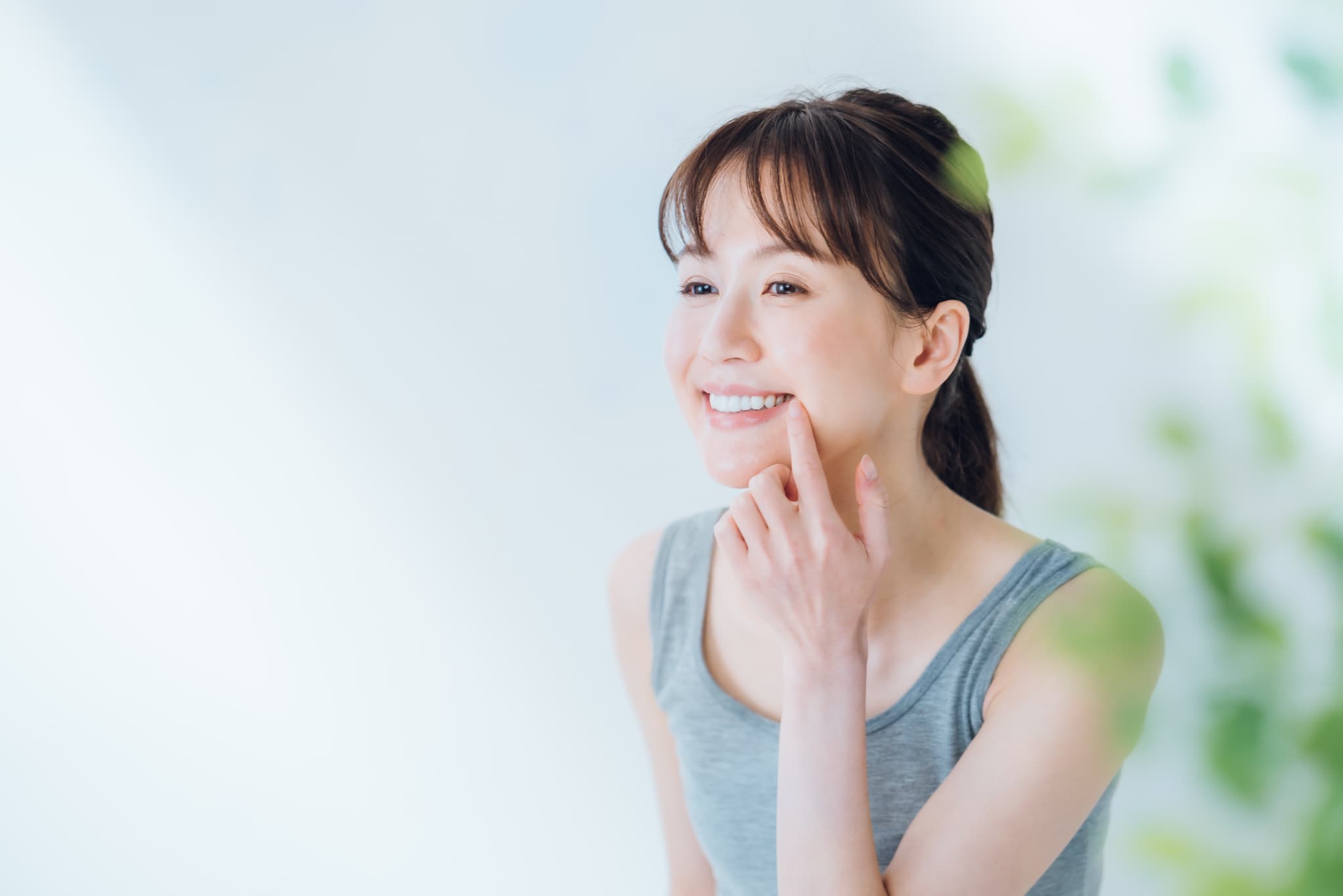 健康な歯や歯ぐきのきれいな口元を指さし笑顔の女性
