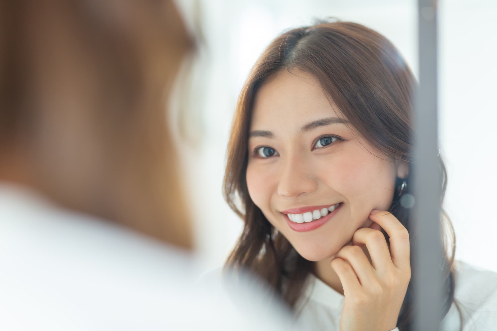 ホワイトニングで白くなった歯を鏡で確認する女性