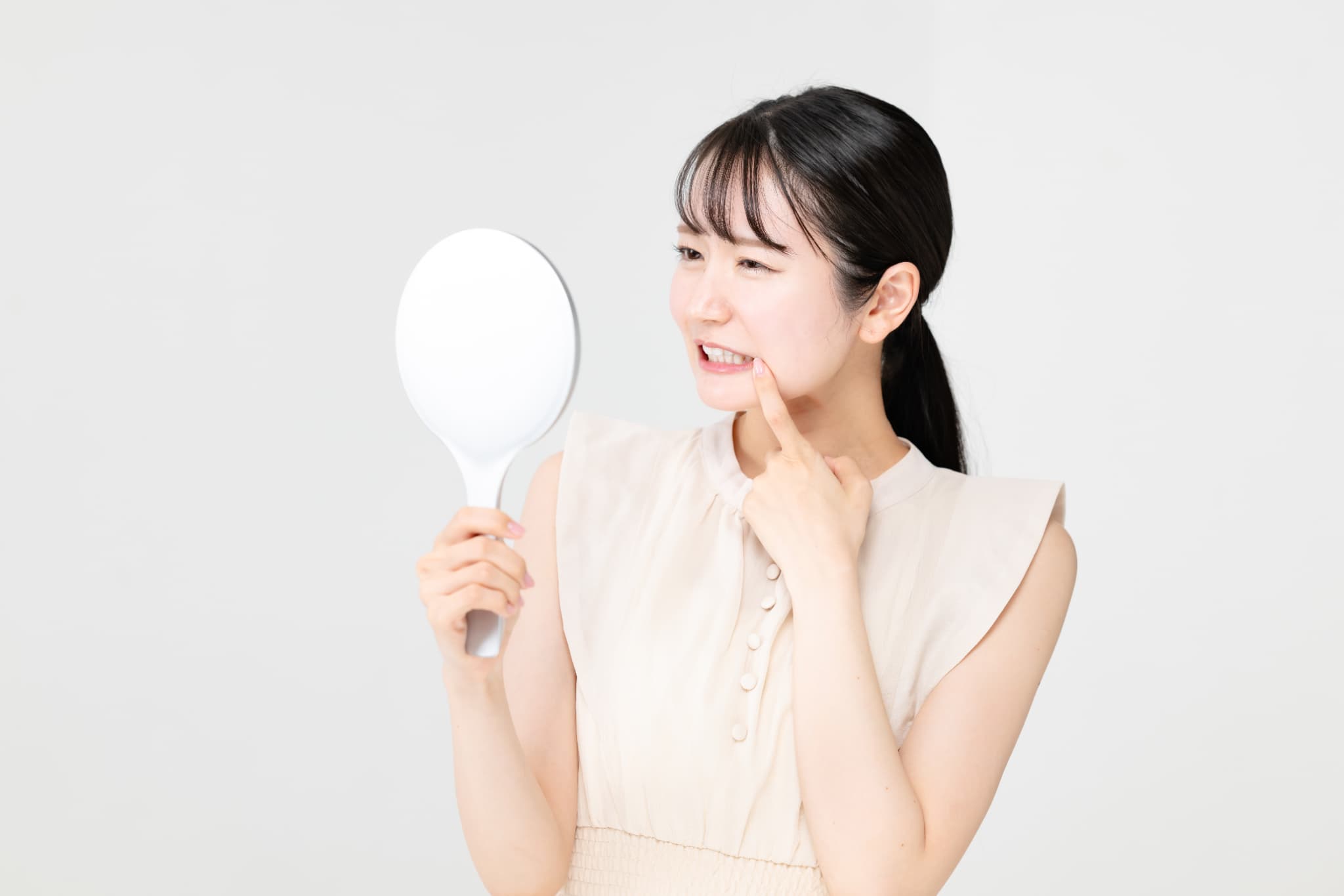 鏡で自分の歯を見て眉を寄せる女性