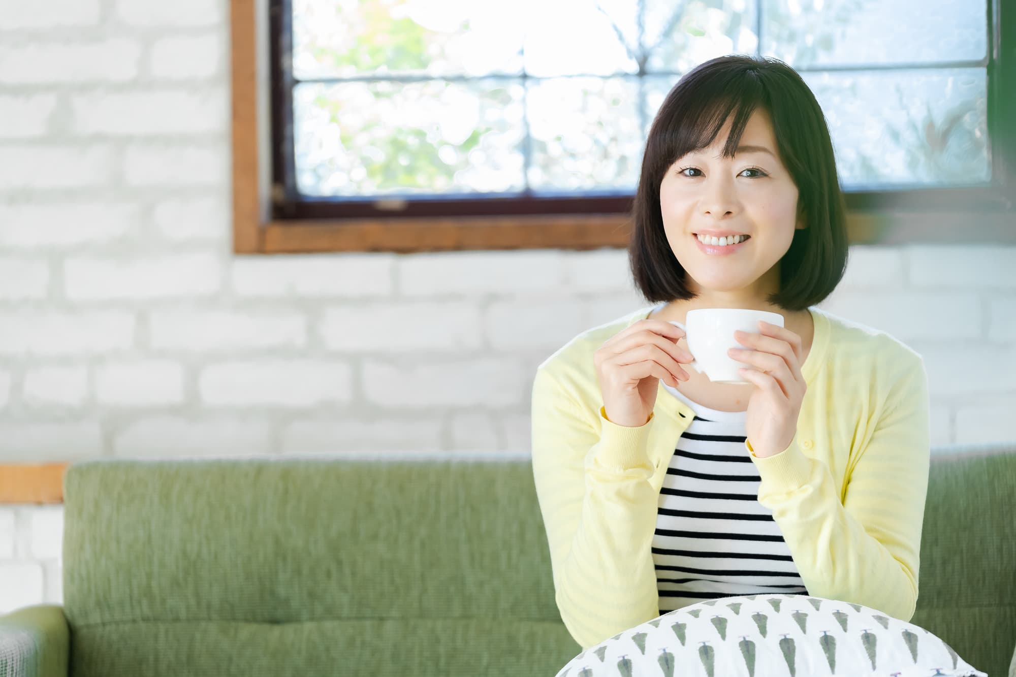 銀歯の下にできた虫歯を治療した女性が笑顔で飲み物を飲んでいるイメージ