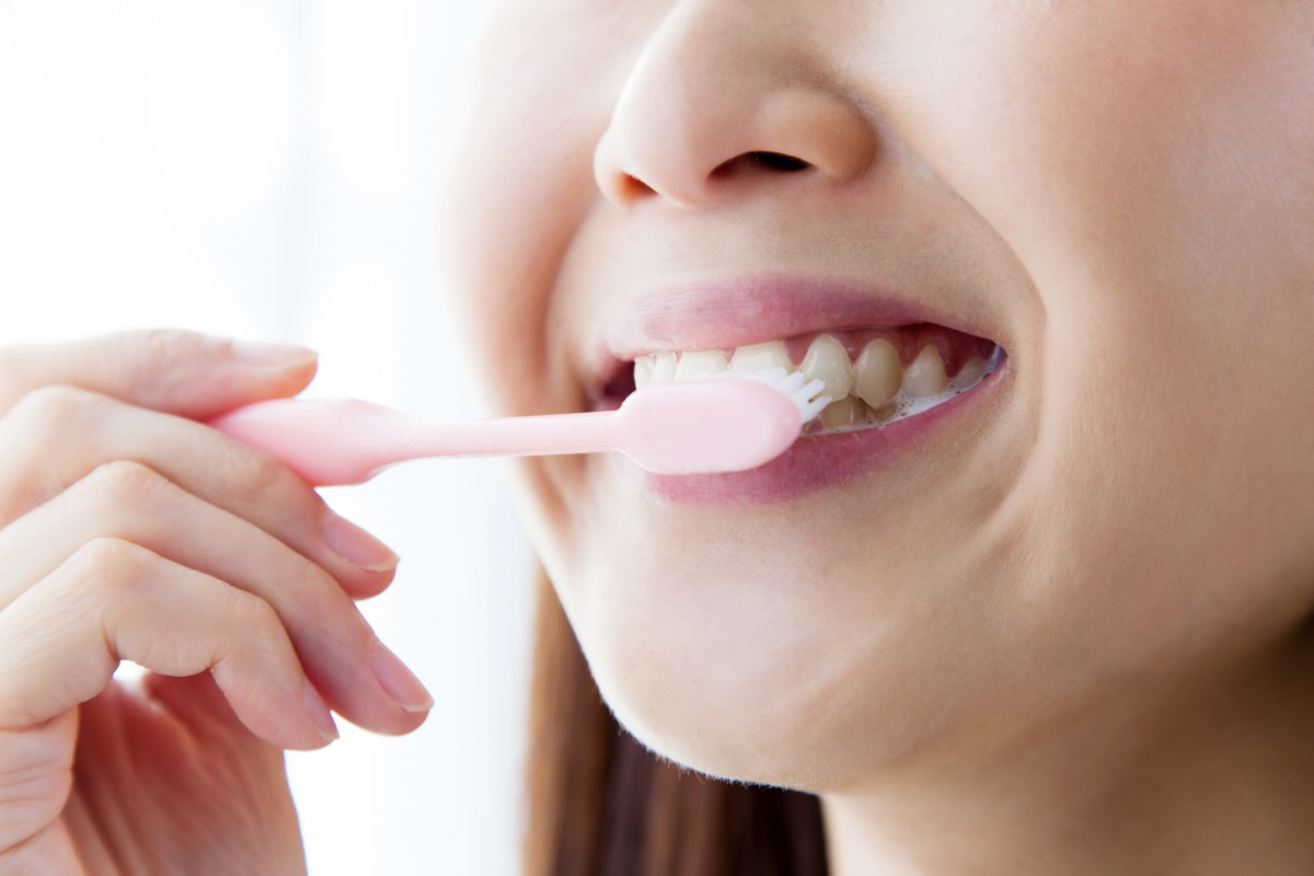 歯周病の進行を防ぐために歯磨きをしている女性