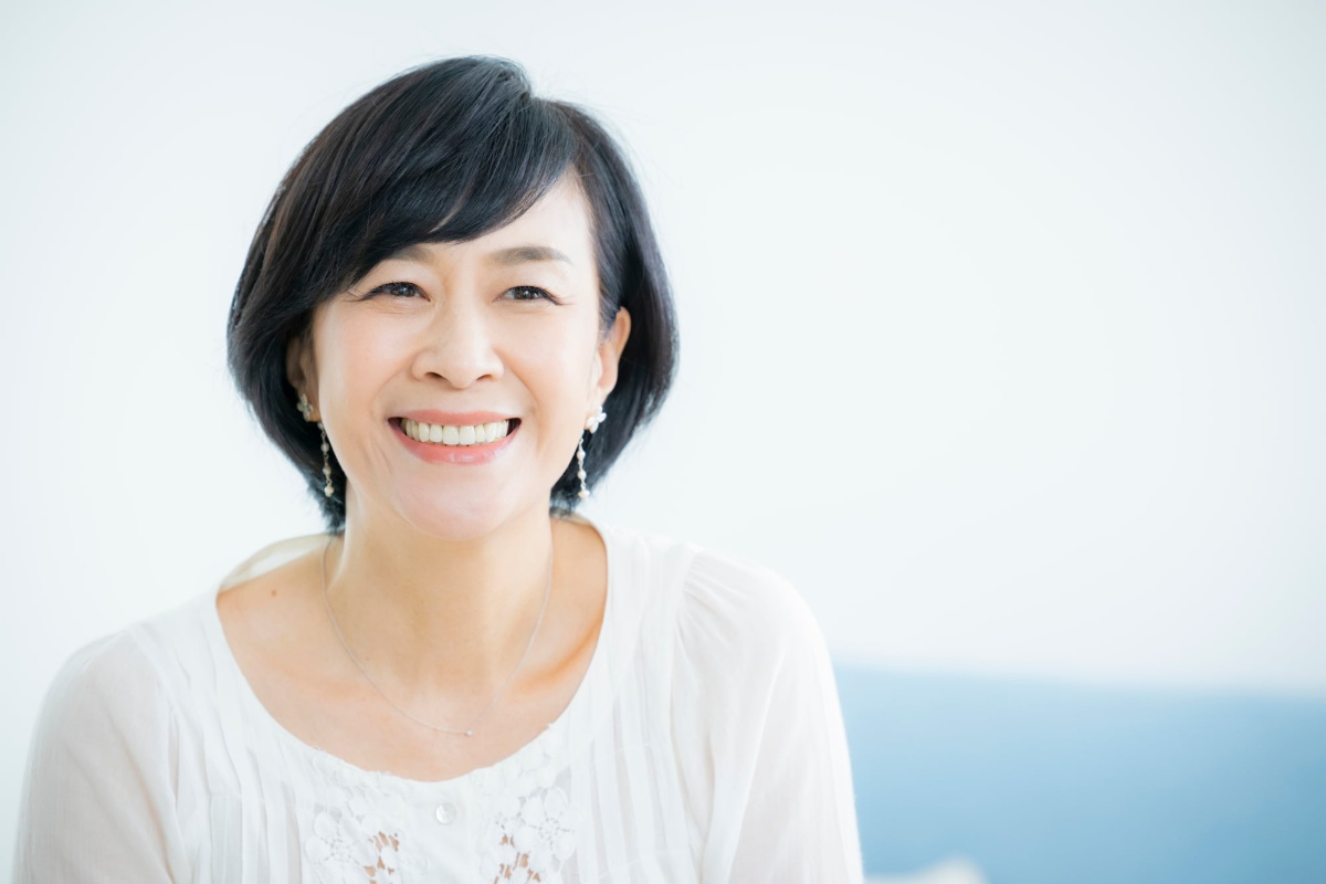 歯科医でPMTCを受けた美しい歯で笑うミドル女性